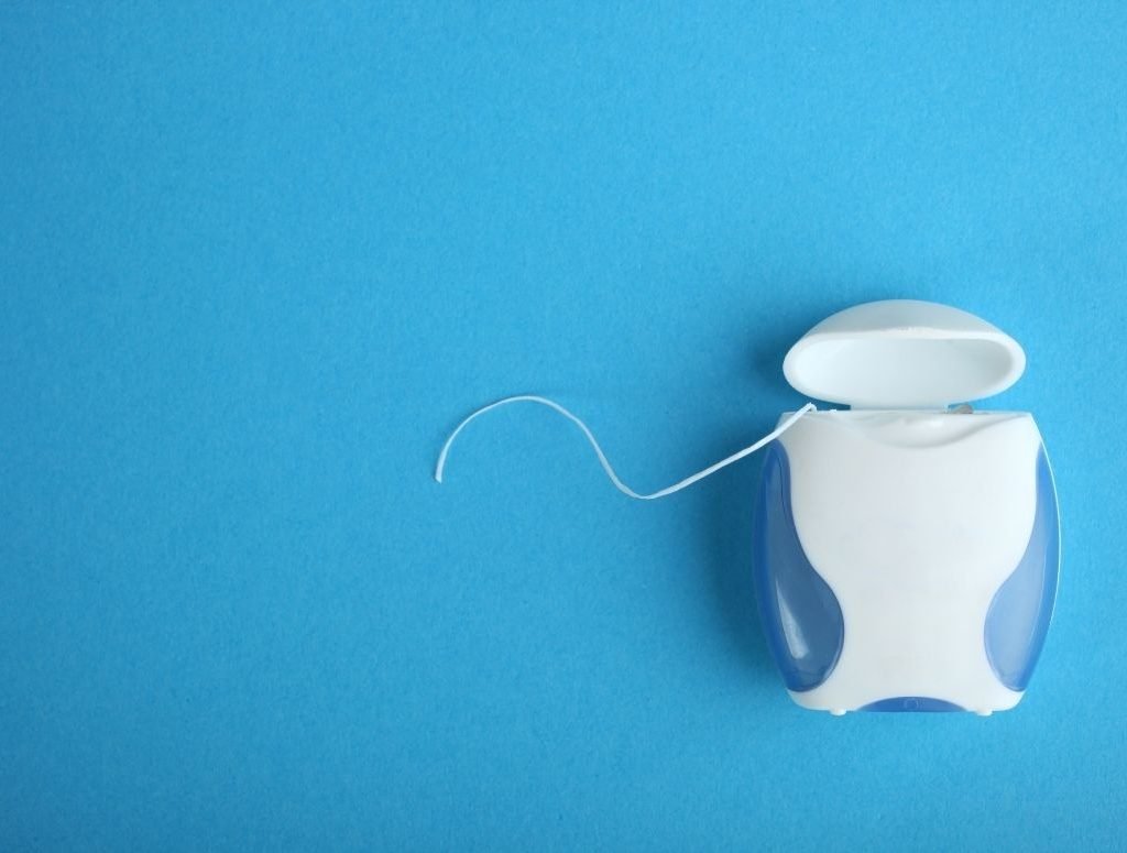 Image of a roll of dental floss on a blue background