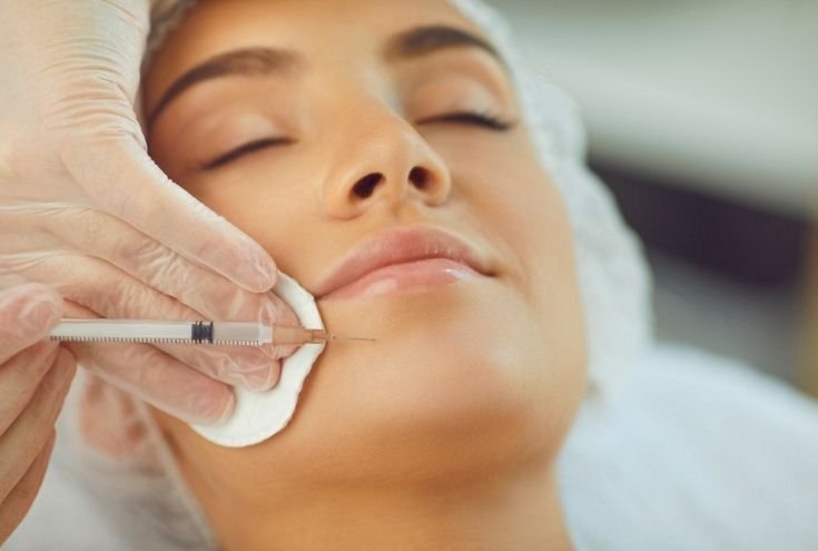 Closeup image of a lady getting a facial injection on her chin