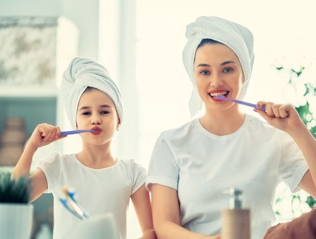 Image of a mom and daughter brushing their teeth