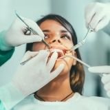 Image of a lady while undergoing composite fillings procedure by two dental professionals