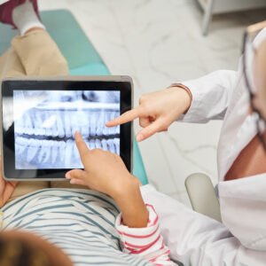 Image of a dental practitioner showing a patient their teeth x-ray or scan results