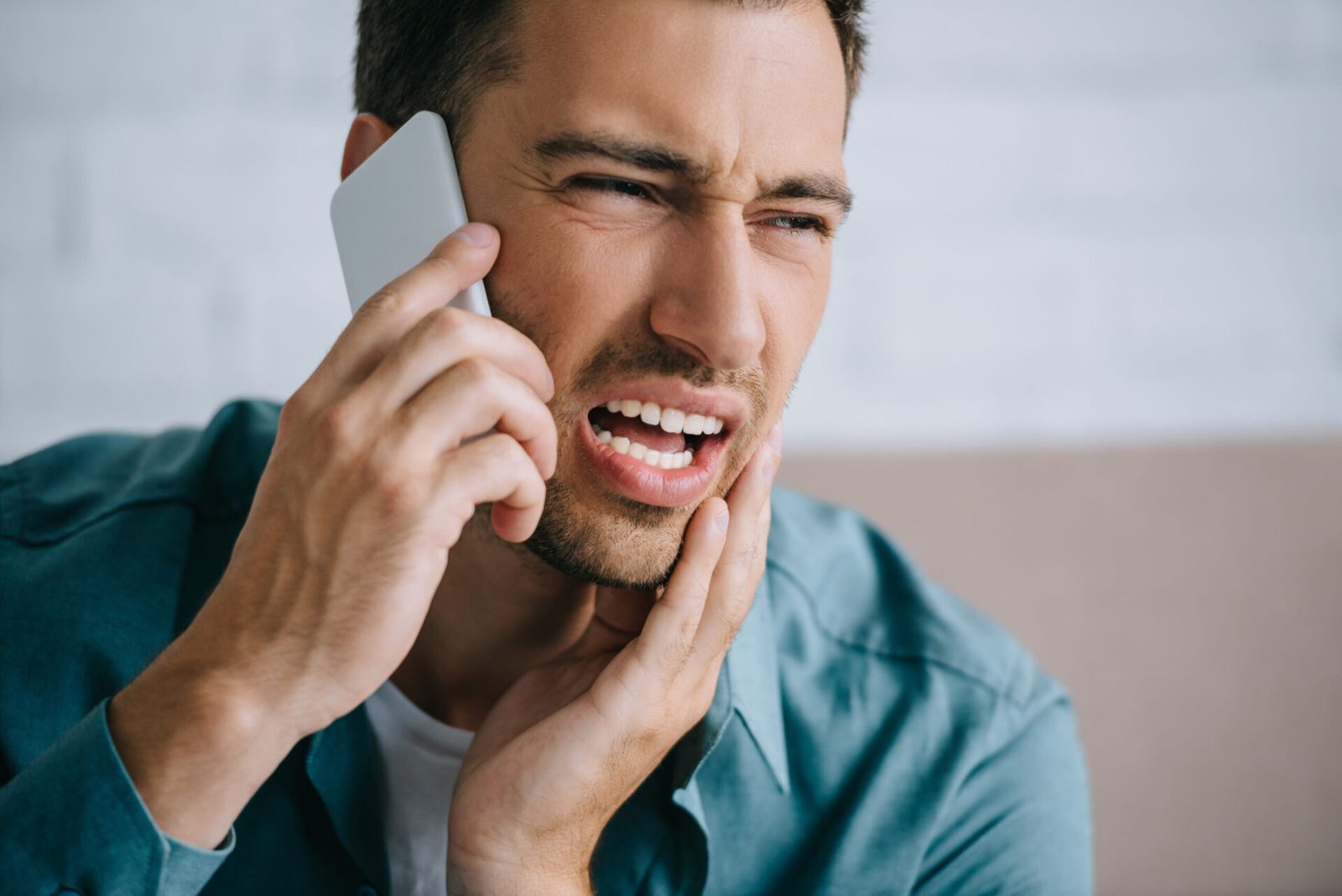 Image of a man who looks like he is in pain calling a dental practitioner