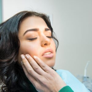 Image of a woman touching her right cheek because of a toothache